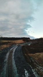 Road passing through landscape against cloudy sky