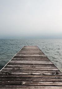 Wooden pier over sea against clear sky