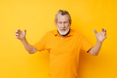 Man with eyes closed standing against yellow background