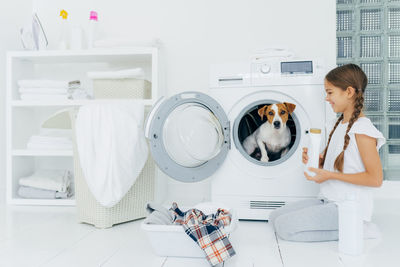 Girl looking at puppy sitting in washing machine