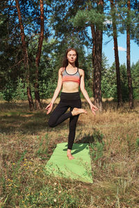 Full length portrait of smiling young woman on field