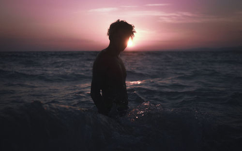 Silhouette man on beach against sky during sunset