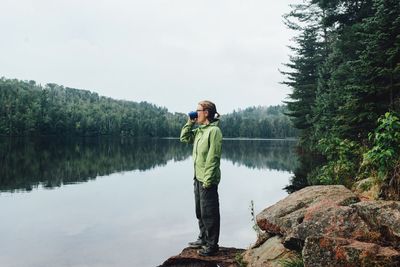 Full length of woman drinking by lake