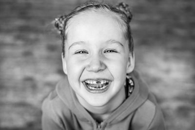 Black and white close-up portrait of a laughing little girl with a missing front tooth.