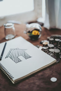 High angle view of notepad with coins on table