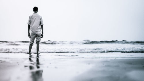 Rear view of man standing against sea at beach