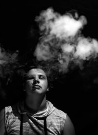 Portrait of man smoking against black background