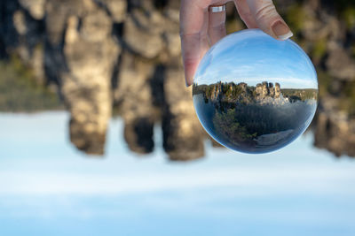 Reflection of person hand holding crystal ball in water