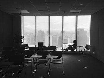 Silhouette woman sitting by window in classroom