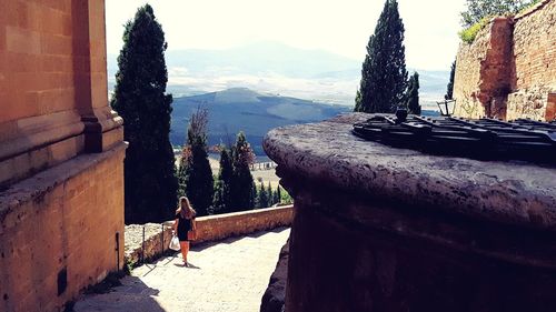 People on retaining wall against mountains