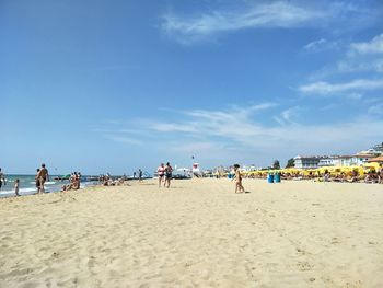 People on beach against blue sky