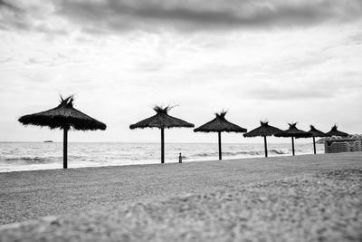 Deck chairs on beach against sky