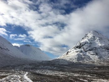 Scenic view of snow covered mountains against cloudy sky