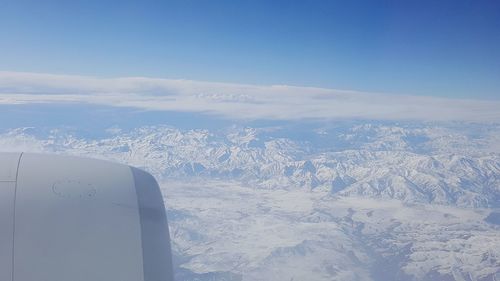 Aerial view of aircraft wing over landscape against sky