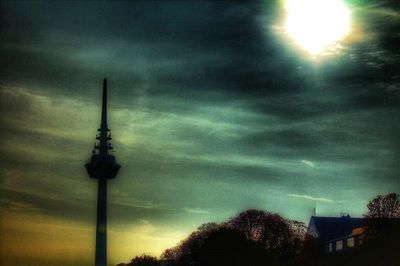 Low angle view of communications tower against cloudy sky