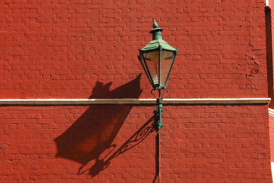 Low angle view of street light against brick wall