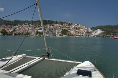 Boats in sea against townscape by mountain