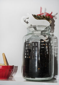 Close-up of glass jar on table against white background