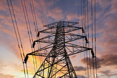 Low angle view of electricity pylon against sky during sunset