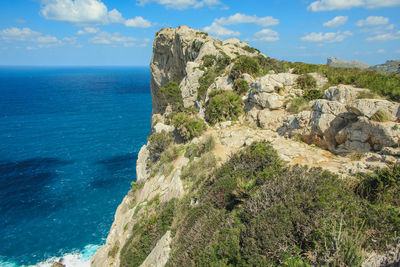 Scenic view of rocks by sea against sky