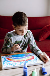 Boy painting at table in living room during summer vacation