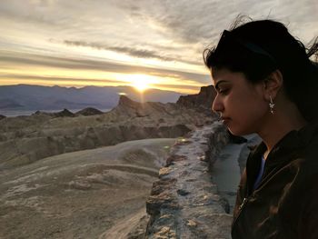 Side view of man looking at mountain during sunset