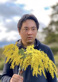 Portrait of man standing on yellow flowering plants