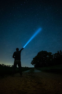 Silhouette man standing on field against sky at night