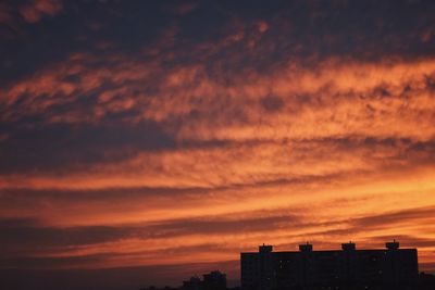 Silhouette buildings against dramatic sky during sunset