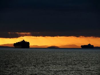 Silhouette boat sailing on sea against sky during sunset