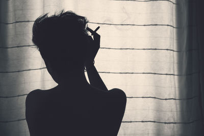 Portrait of silhouette woman against wall at home