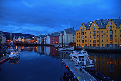 Boats moored at harbor by buildings in city at dusk