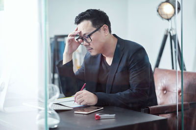 Worried businessman working while sitting on table