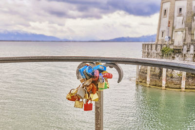 Padlocks on bridge over river against sky