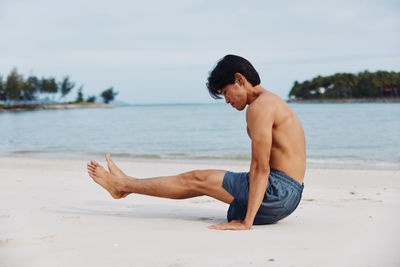 Portrait of shirtless young man standing at beach