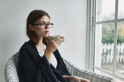 Beautiful young woman drinking glass window