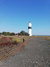 Lighthouse by building against clear blue sky