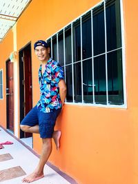 Portrait of smiling man standing by wall