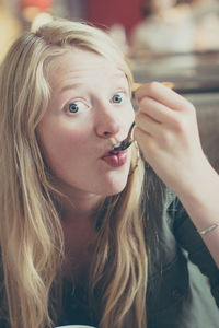 Portrait of beautiful young woman with spoon in mouth