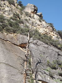 Low angle view of rocks on mountain against clear sky