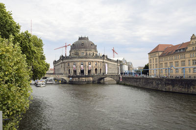 Canal amidst buildings in city against sky