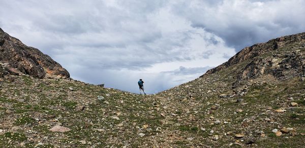 Man standing on rock against sky