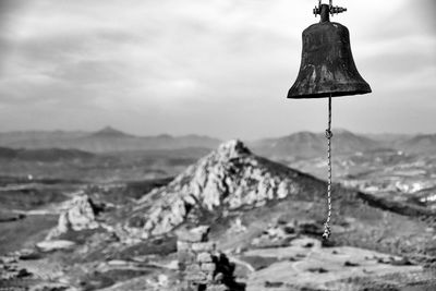 Old bell over landscape against sky