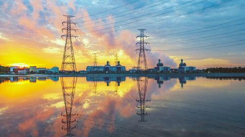 Reflection of electricity pylon against sky during sunset