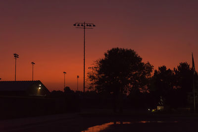 Street light by silhouette trees against sky during sunset