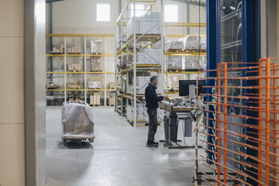 Full length of worker standing at desk in lumber industry