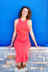 Portrait of young woman standing against brick wall