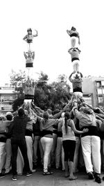 Rear view of people standing on street against sky