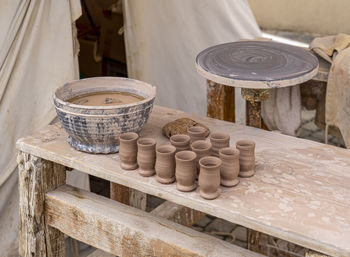 Traditional ceramic manufacturing with throwing table, beakers and bowl on wooden table