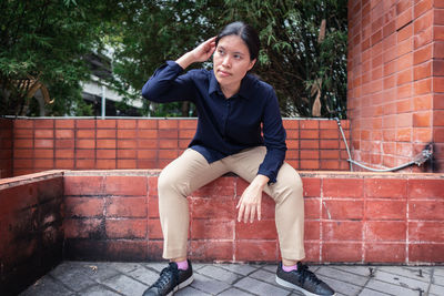 Full length of woman sitting on wall